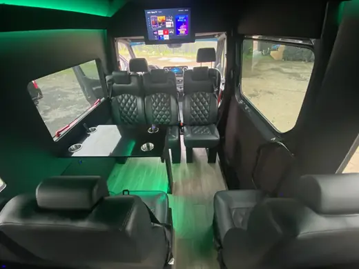 Executive Sprinter cabin with dark seats and green ceiling lighting — About SprinterVansRental.com