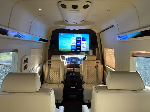 Jet Sprinter cream seats facing a cabin screen — About SprinterVansRental.com
